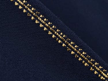 Extreme macro texture of dark navy cotton twill fabric, showing the precise diagonal weave pattern under sharp studio lighting.