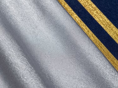 Macro shot of silver-grey polyester fabric texture, displaying fine synthetic fibers and structured weave under cool metallic light.