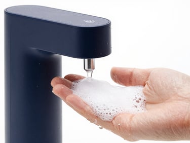 Close-up of a modern automatic soap dispenser releasing foam onto a hand, crisp water droplets, high-key lighting