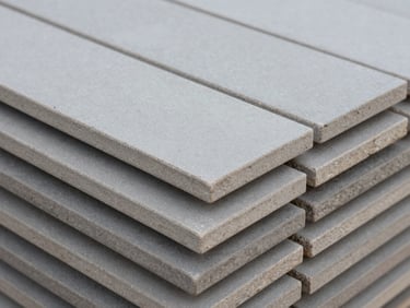 Close-up of stacked grey porcelain tiles showing textured matte surface, cool overcast daylight