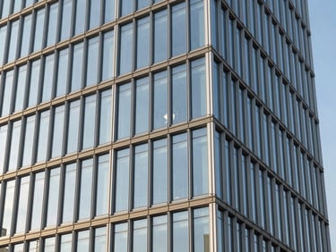Modern glass and steel office facade reflecting the blue sky, clean geometric lines, crisp daylight, 35mm lens