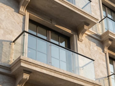 Close-up architectural shot of restored classic balcony with modern glass elements, golden hour light, high contrast, elegant neutral tones