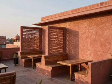 Warm editorial photography of a serene rooftop cafe in Jaipur, terracotta-washed walls, minimal wooden seating, soft evening shadows of jali screens, 35mm lens.