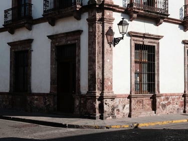 Gritty street corner in historic center of San Luis Potosí, old stone facade, high-contrast shadows