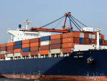 Wide shot of a large container ship being loaded at a busy port, high contrast, deep navy and orange tones, sharp focus