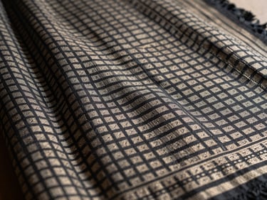 Macro photograph of a partially woven Patan Patola saree, showing the incredibly sharp geometric grid of the double-ikat pattern, natural daylight.