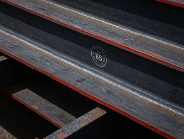 Industrial-grade steel beam with a clear certification stamp, harsh direct sunlight, high-contrast black and red tones, deep shadows, 35mm lens