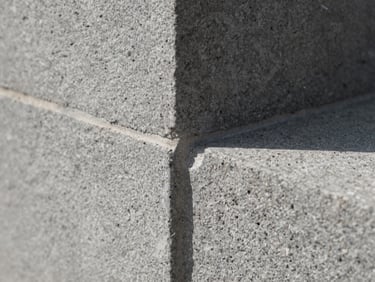 Extreme close-up of stonework joints freshly pointed, natural grey aggregate, documentary craft detail, daylight raking across the surface to reveal texture