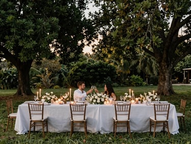 Elegant outdoor anniversary dinner setup under a canopy of trees, with a beautifully decorated long table, soft lighting, and a couple toasting.