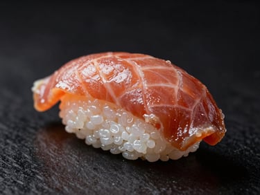 Nigiri de atum selado com foie gras, detalhe do corte e da textura, fundo escuro.