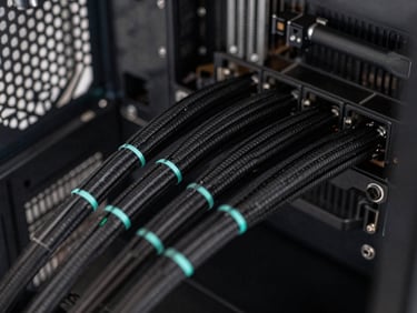 Close-up of clean cable management inside a modern gaming PC, neat black sleeved cables, subtle cyan accent light