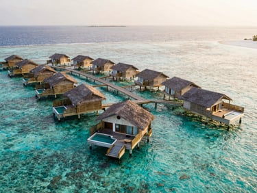 Aerial view of luxury overwater bungalows in the Maldives, clear turquoise water, white sand, soft natural light, 35mm, no people.