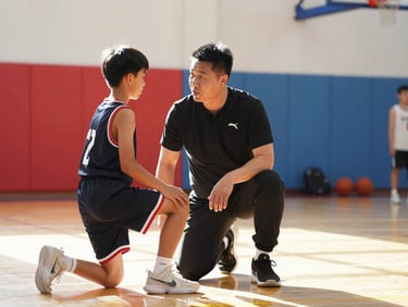 A coach kneeling to talk to a young basketball player in a brightly lit indoor gym, warm high-key lighting, sharp focus.