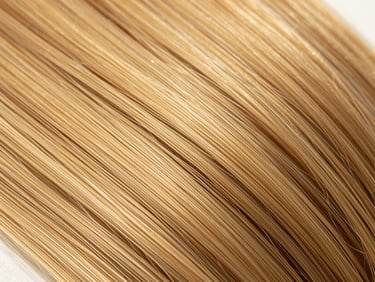 Macro close-up of premium double-drawn hair extensions catching natural golden hour sunlight, highlighting clean texture and sheen