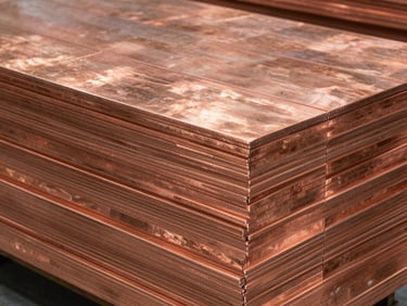 Close-up of stacked copper flats in a clean warehouse, crisp high-contrast studio lighting showing deep metallic red-orange tones, 35mm