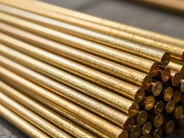 Macro shot of stacked polished brass rods, bright natural warehouse light highlighting metallic gold sheen, sharp focus, 35mm