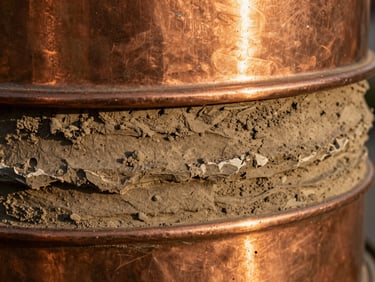 Extreme close-up of textured copper and raw clay strata, warm golden hour light highlighting the physical materiality and rugged utility.