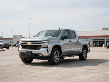 Wide 3/4-angle shot of a silver 2022 Chevrolet Silverado parked on an empty dealer lot, bright overcast daylight, crisp shadows, concrete surface, no people