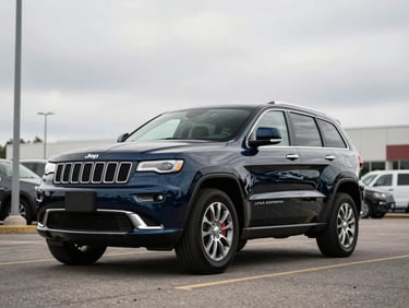 3/4-angle shot of a dark blue 2021 Jeep Grand Cherokee on a flat dealer lot, overcast daylight, wide environmental framing, no people