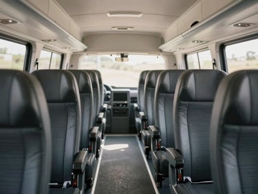 Spacious interior of a Tempo Traveller, clean aisle, individual high-back seats with headrests, bright afternoon light.