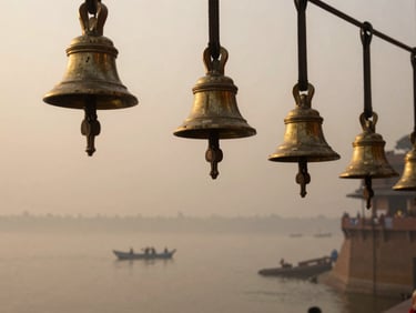 Soft morning mist over the Ganga, weathered brass bells catching the hazy golden hour light of Varanasi