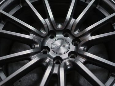 Extreme close-up of a custom multi-piece forged wheel, precision billet-aluminum machining details, dramatic low-key studio lighting, shallow depth of field, 35mm anamorphic