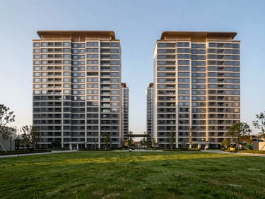 Symmetrical wide-angle architectural rendering of modern high-rise residential towers under clear golden hour light, manicured green lawns in foreground