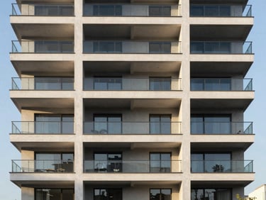 Modern residential apartment building exterior with clean lines, glass balconies, bright afternoon sun highlighting structural symmetry
