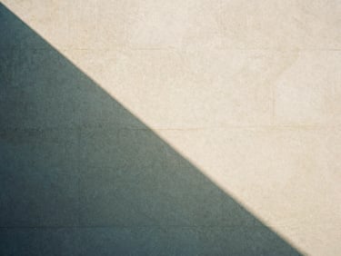 Abstract geometric shadows on a warm sand concrete wall, clean minimalist composition, soft daylight, 35mm film