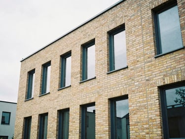 Detail crop of a modern residential brick facade in Reutlingen, soft overcast daylight, clean architectural lines, warm sand and navy tones, 35mm film
