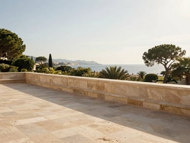 Wide environmental shot of a sunlit stone terrace overlooking Mediterranean greenery in Cannes, soft golden hour light