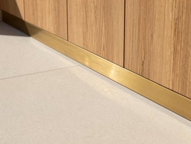 Close-up of premium material transition, seamless micro-cement floor meeting brushed brass profile and warm oak paneling, sharp details.