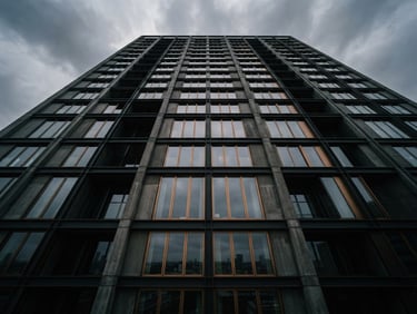 High-angle architectural perspective of a minimalist concrete and steel skyscraper facade, moody overcast daylight, deep obsidian shadows, sharp focus, 35mm