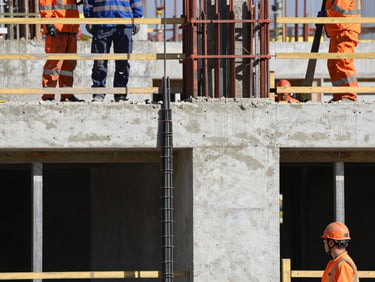 Close-up of a structural concrete pour at a modern construction site, workers in clean safety gear and orange helmets, daylight.