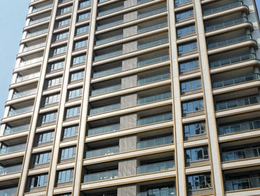 Modern high-rise residential building facade with clean structural lines, bathed in bright natural daylight, crisp shadows, architectural wide angle, editorial real estate photography, deep emerald and gold accents, 35mm