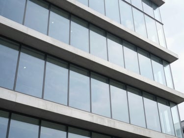 Architectural elevation of a modern commercial building facade with large aluminum glass panels reflecting the sky, natural light