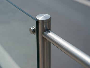 Macro shot of a stainless steel guardrail post holding a heavy glass panel, architectural daylight, 50mm lens