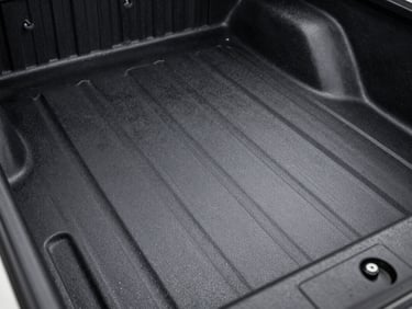 Close-up of a textured matte black polyurethane bedliner on a truck bed, high-contrast gritty detail, metallic tones.