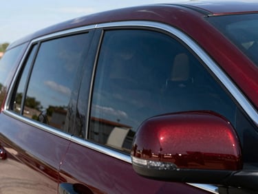 Low-angle vehicle profile showcasing premium dark ceramic window tint reflecting bright Texas daylight, sharp contrast