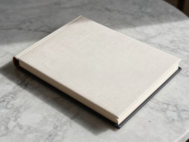 Minimalist close-up of a premium textile-bound wedding album resting on a clean travertine marble surface, soft natural side-lighting, elegant shadows.