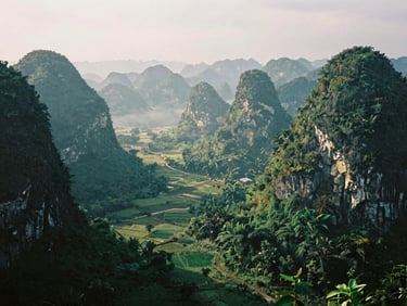 Dramatic view of Ma Phuc Pass in Cao Bang winding through steep limestone karst mountains, misty valley below, lush green vegetation, overcast cinematic lighting, 35mm film.