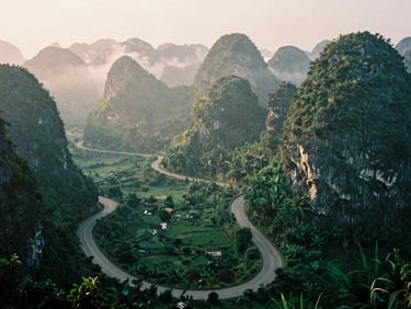Misty morning view of Ma Phuc pass winding through steep limestone karst mountains, winding asphalt road, soft golden sunlight filtering through clouds, cinematic 35mm photography.