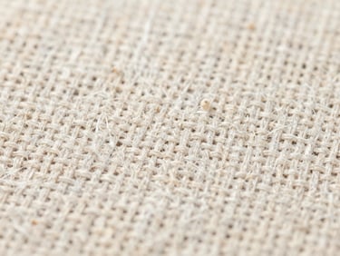 Macro close-up of raw linen fibers and woven cotton threads under neutral daylight, high-resolution textile texture.