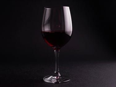 Crystal wine glass with deep red wine, catching low light, dark background, elegant and mysterious atmosphere