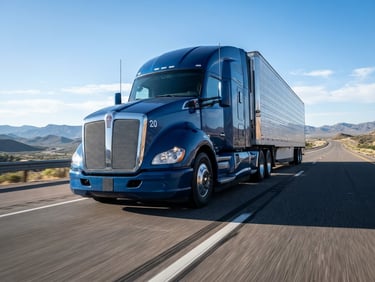 Low-angle powerful perspective of a modern blue freight truck on an open highway under crisp morning light, high-contrast, clean lines.