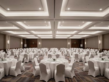Panoramic shot of an empty luxury banquet hall, tall ceilings with recessed lighting casting cool white light across draped round tables, no guests, architectural symmetry prominent