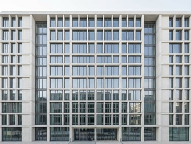 Straight-on architectural shot of a modern concrete building facade, sharp geometric lines, bright neutral daylight, crisp shadows, desaturated blue tones