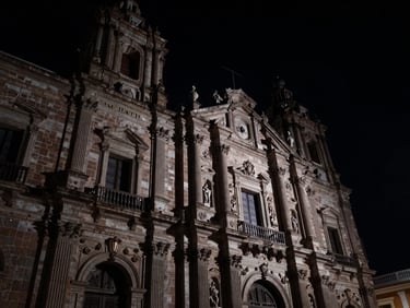 Low-angle shot of imposing judicial architecture in Morelia under a dark night sky, harsh side-lighting, deep shadows