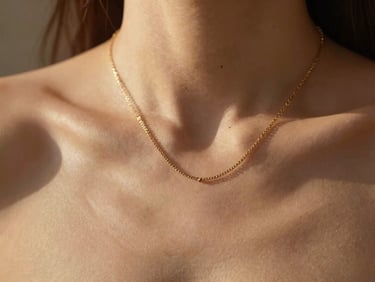 Delicate gold necklace layered on a model's collarbone, shallow depth of field, warm light