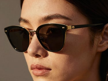 Close-up of elegant sunglasses on a model's face, architectural shadows, editorial crop
